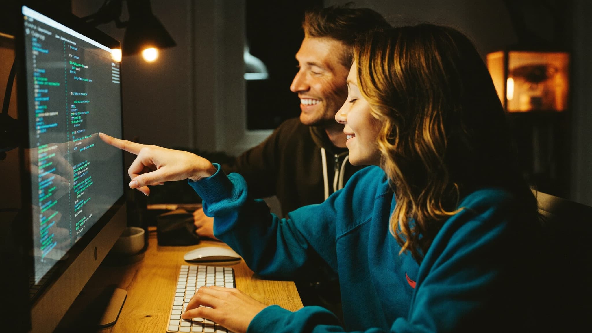 A parent and their teenager smiling at a computer, building an AI project together